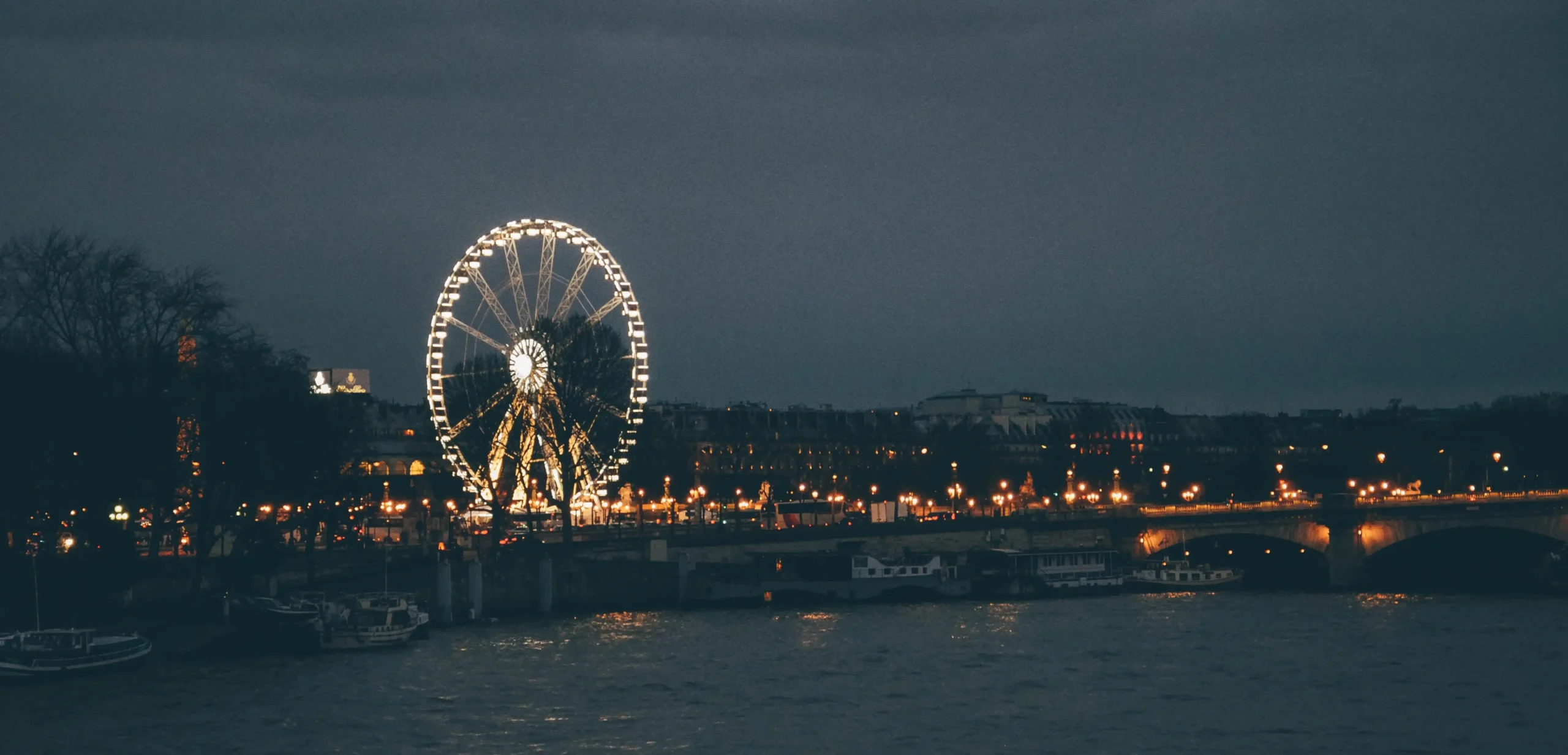 ferris-wheel-surrounded-by-river-buildings-cloudy-sky-night-paris